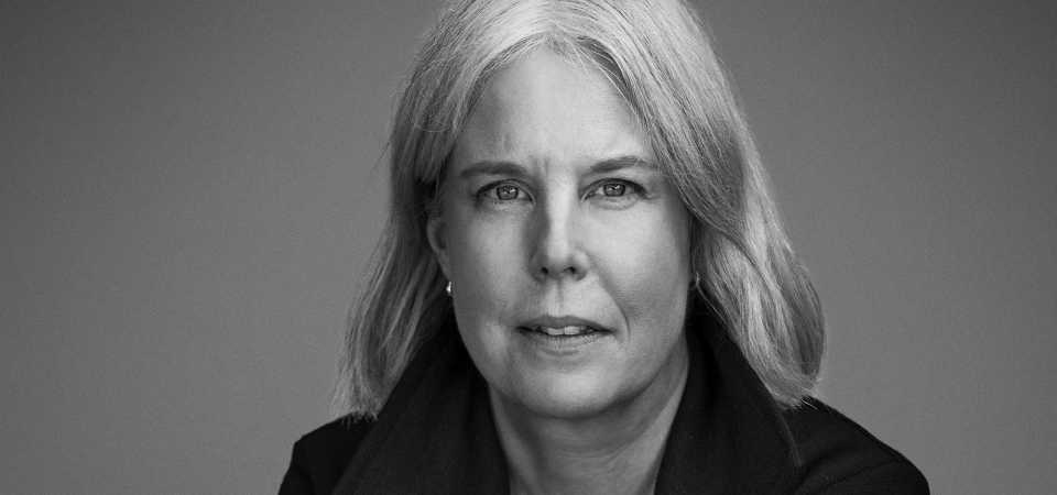 Anna Nordlund Svartvit bild på Anna Nordlund som sitter på en stol bakochfram med armarna i kors.