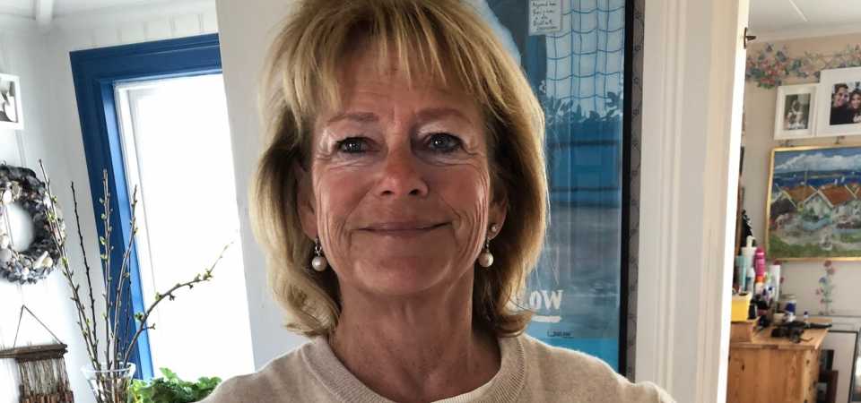 Lena Adelsohn Liljeroth Lena Adelsohn Liljeroth står med händerna i midjan och har på sig en stickad tröja med två räkor som bildar ett hjärta.